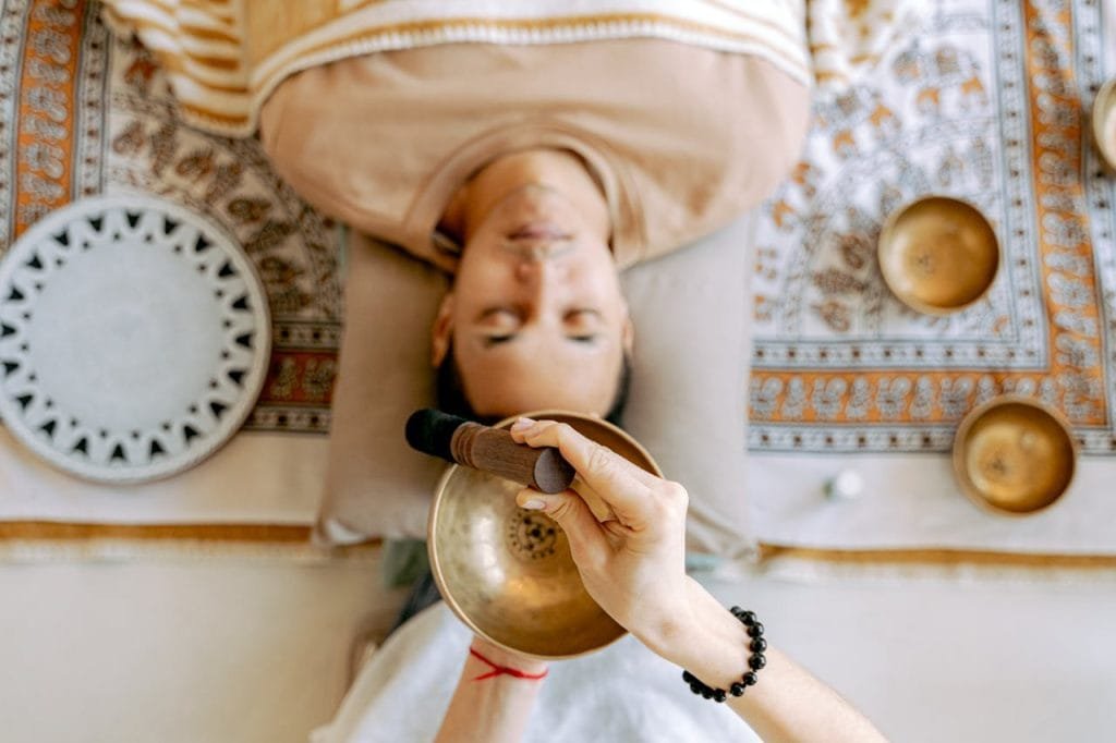 man-relaxing-while-listening-to-sounds-6252164 A man experiencing deep relaxation during a sound therapy session with Tibetan singing bowls for holistic wellness.