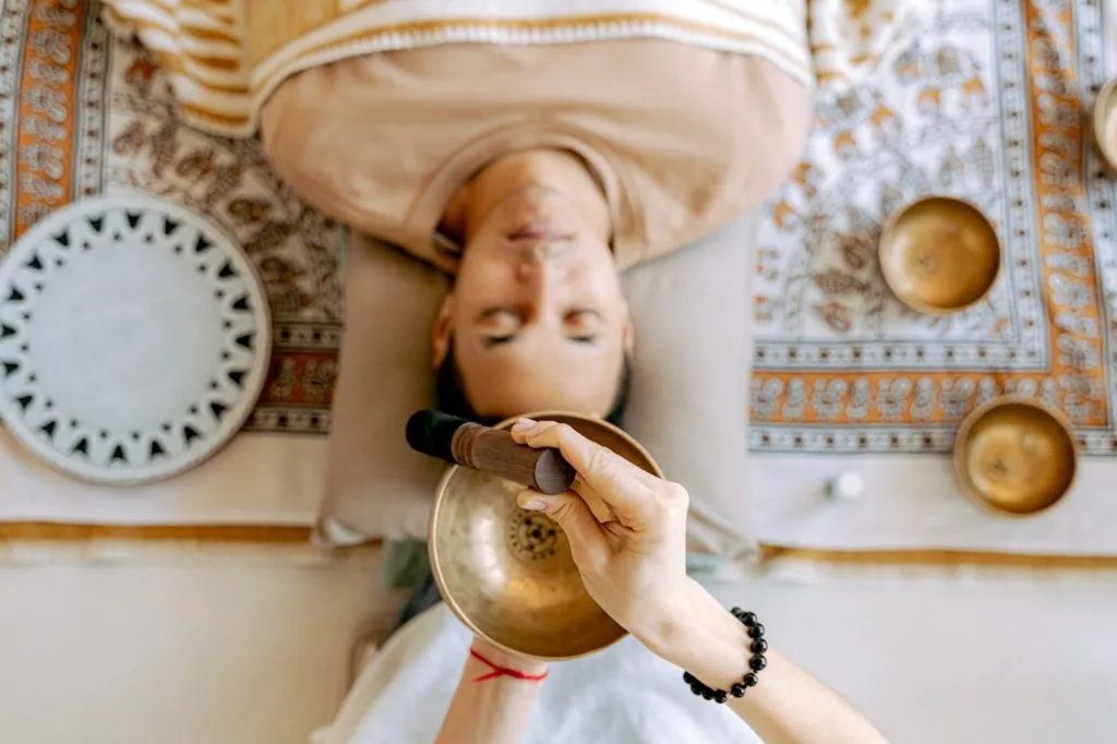 man-relaxing-while-listening-to-sounds-6252164 A man experiencing deep relaxation during a sound therapy session with Tibetan singing bowls for holistic wellness.
